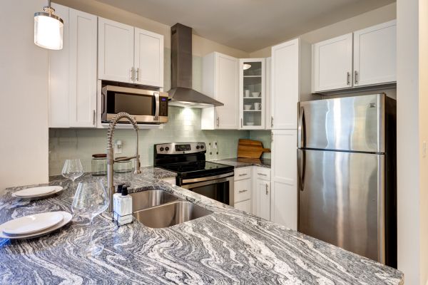 Modern kitchen with marble countertops, stainless steel appliances, and bar seating for two.