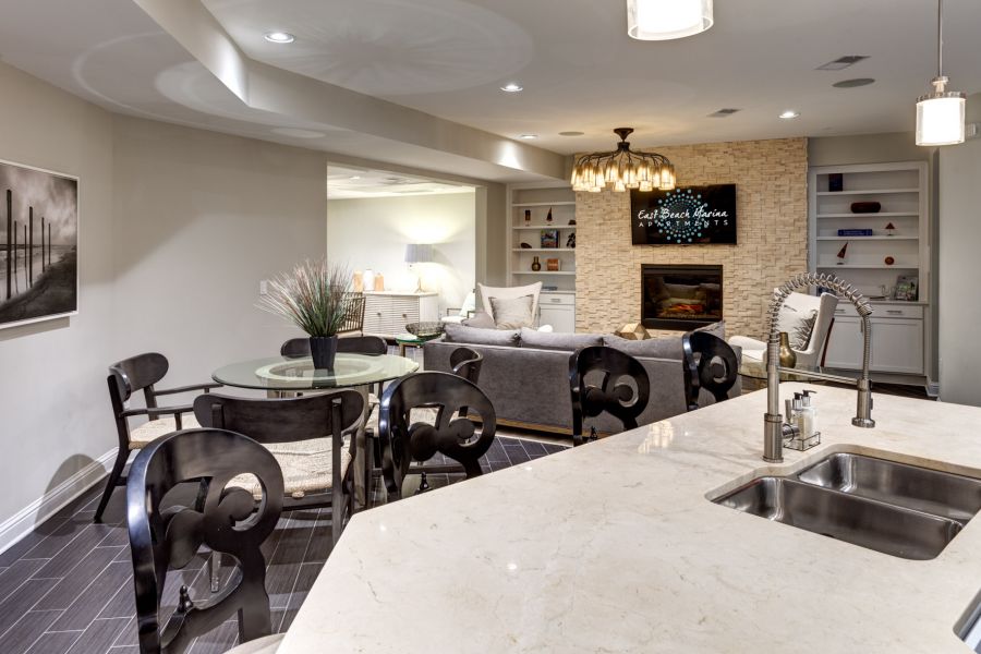 Modern open-concept living area with kitchen island, dining table, and cozy lounge near a fireplace.