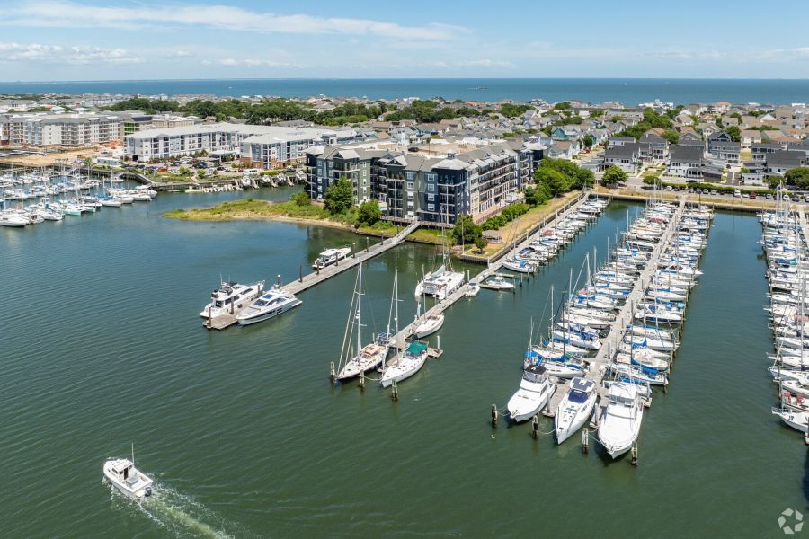 Aerial view of a marina with docked boats, waterfront apartments, and houses near the coastline.